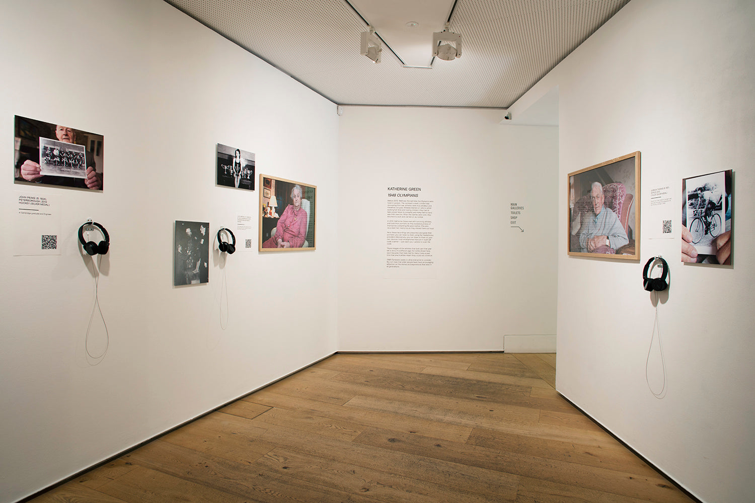 Art gallery with framed photographs and audio devices on white walls.