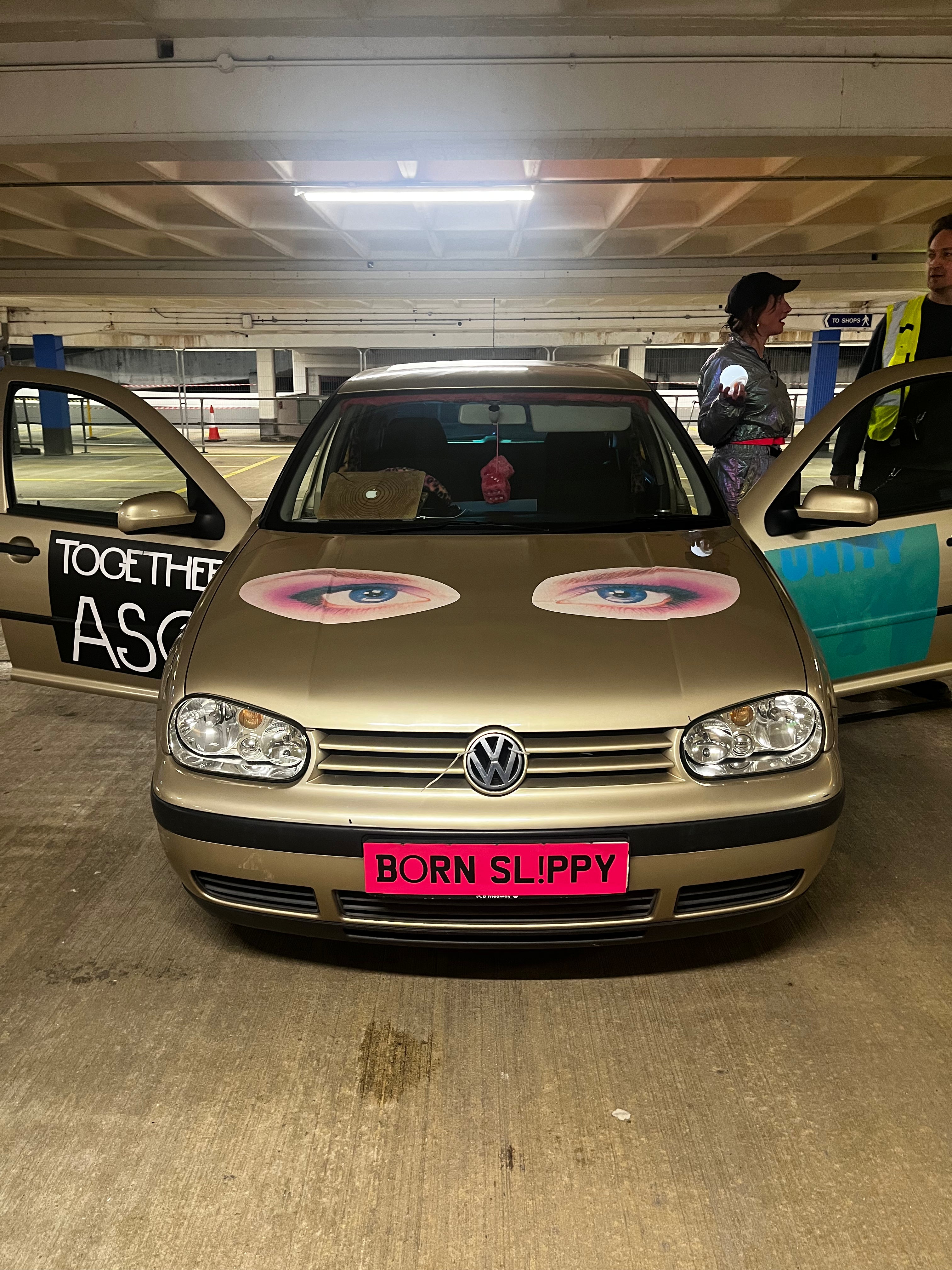 Gold Volkswagen car with decorative stickers in a parking garage