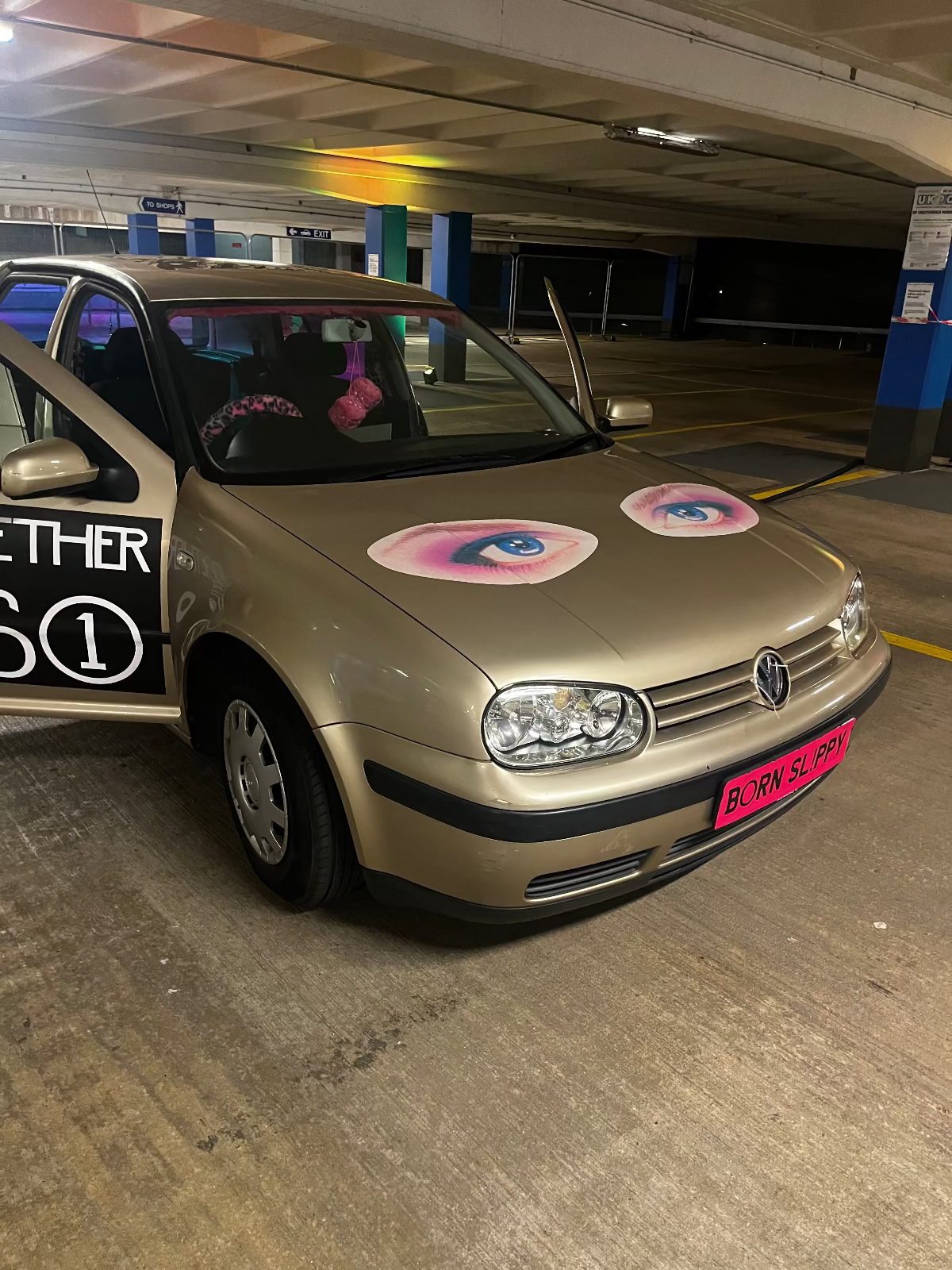 Gold car with decorative stickers in a parking garage