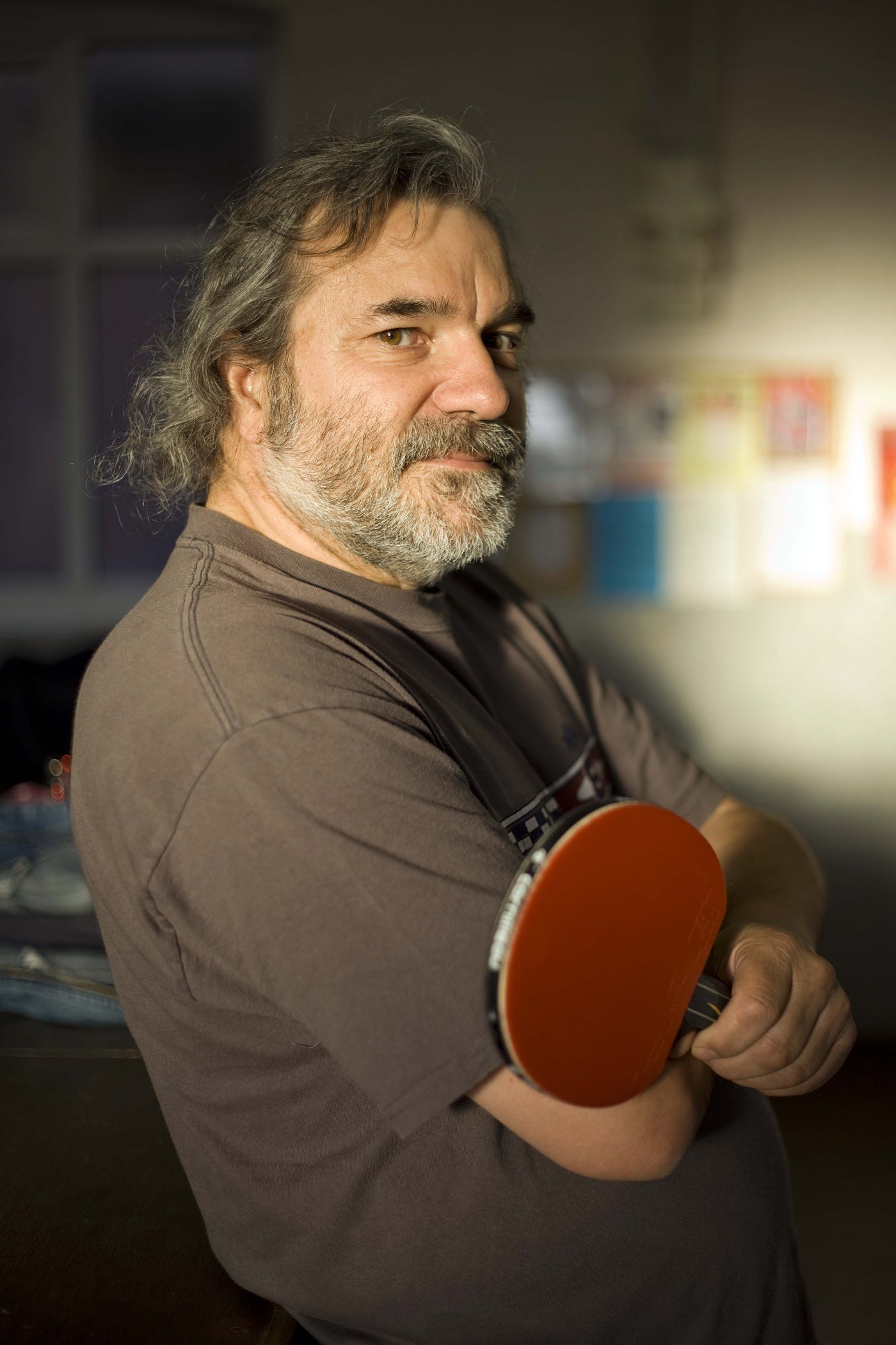 Man holding a ping pong paddle with a blurred background