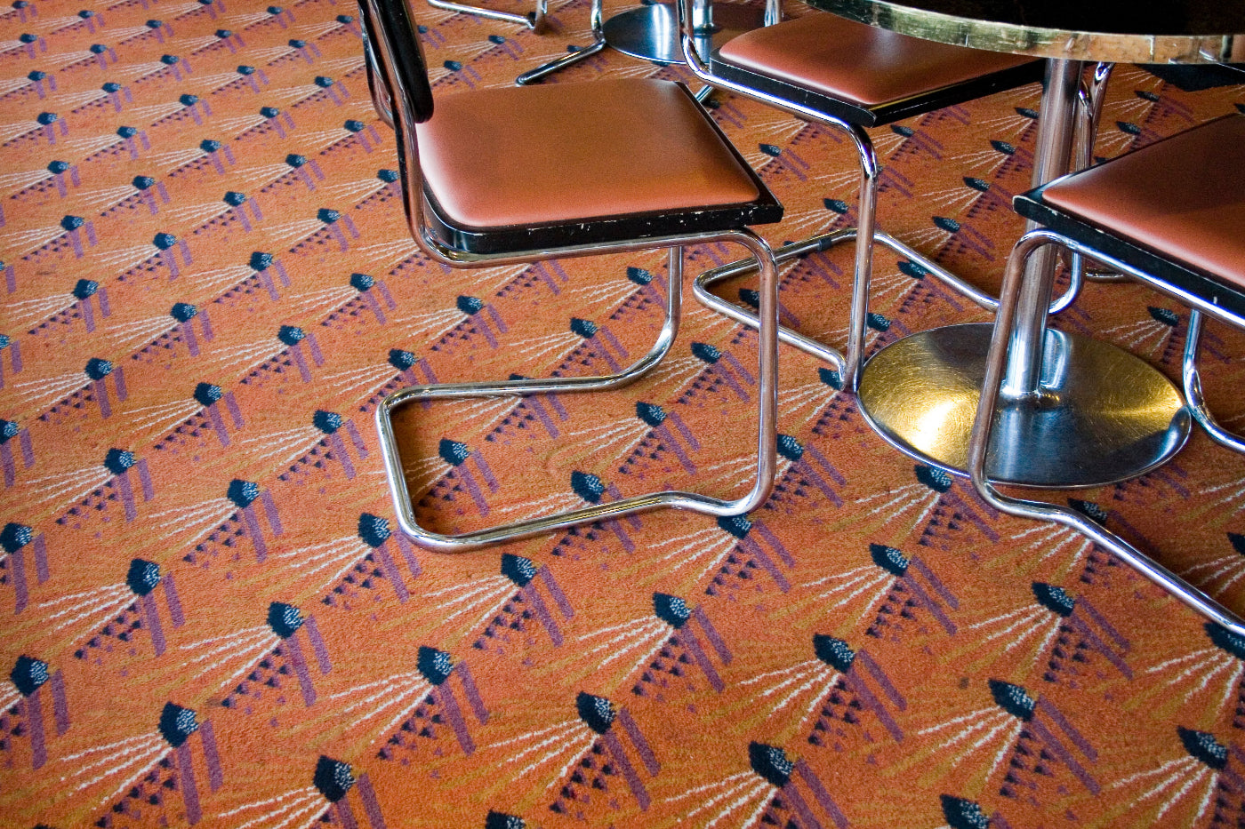 Brown chairs with metal legs on a patterned carpet