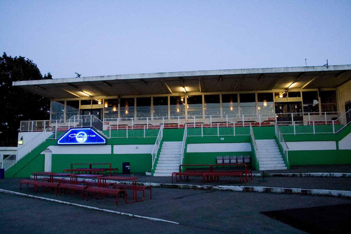 Stadium with green and white seats and a blue logo on the wall.