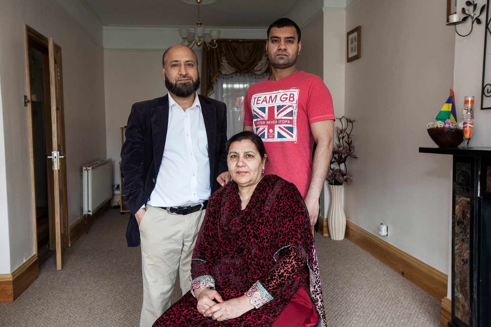 Three people standing in a room with a Union Jack t-shirt and decorative items.