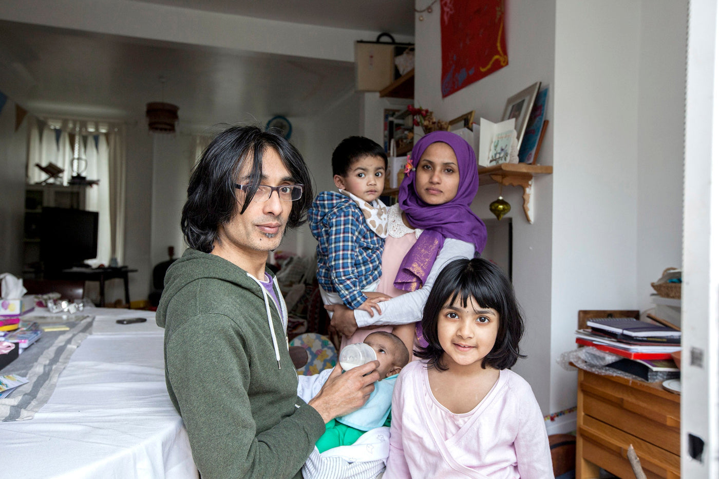 Family of five in a living room setting with a child being held.
