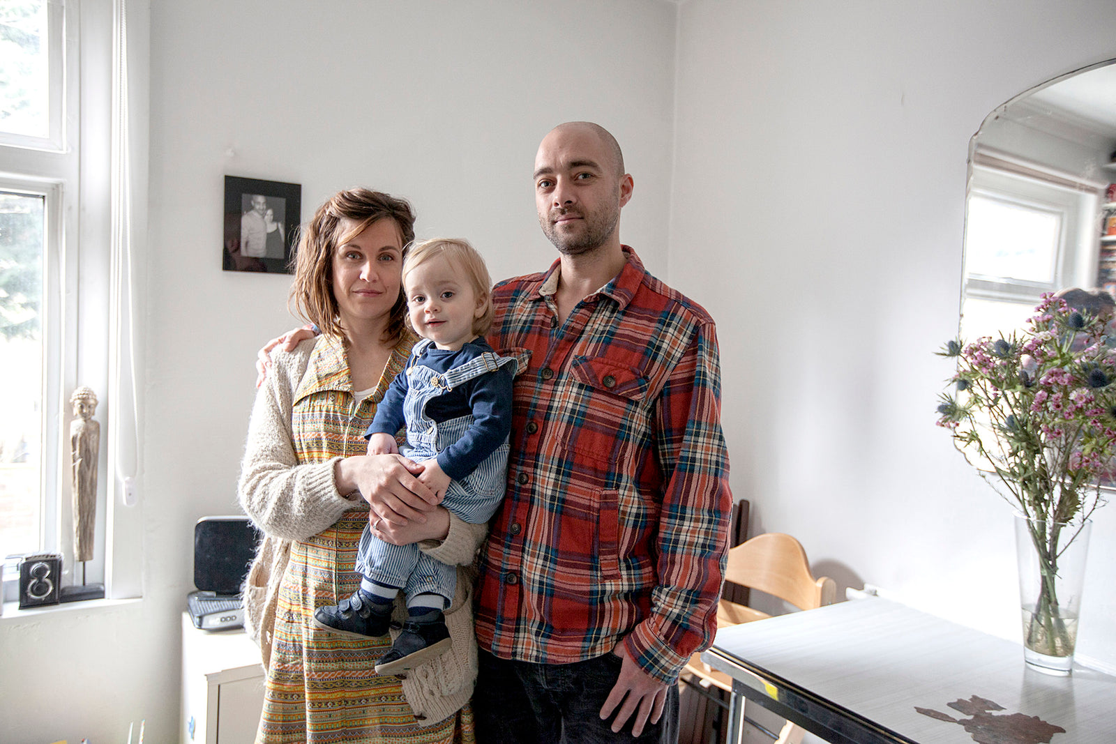 Family of three in a home setting with a child being held by the woman.