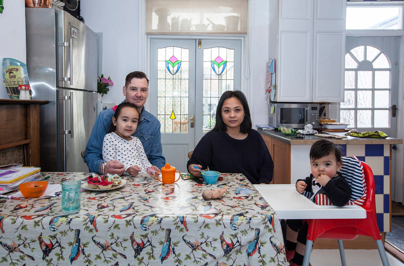 Family of four in a kitchen setting with a table and chairs.