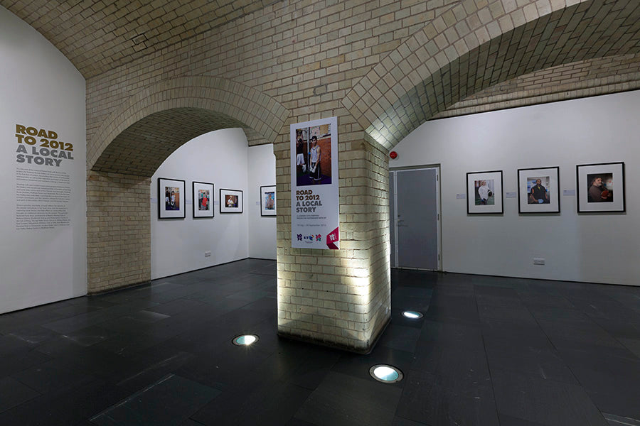 Art gallery with framed pictures on the walls and a central light fixture.