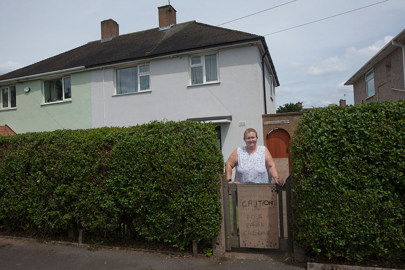 Person standing in front of a house with a 'CAUTION' sign
