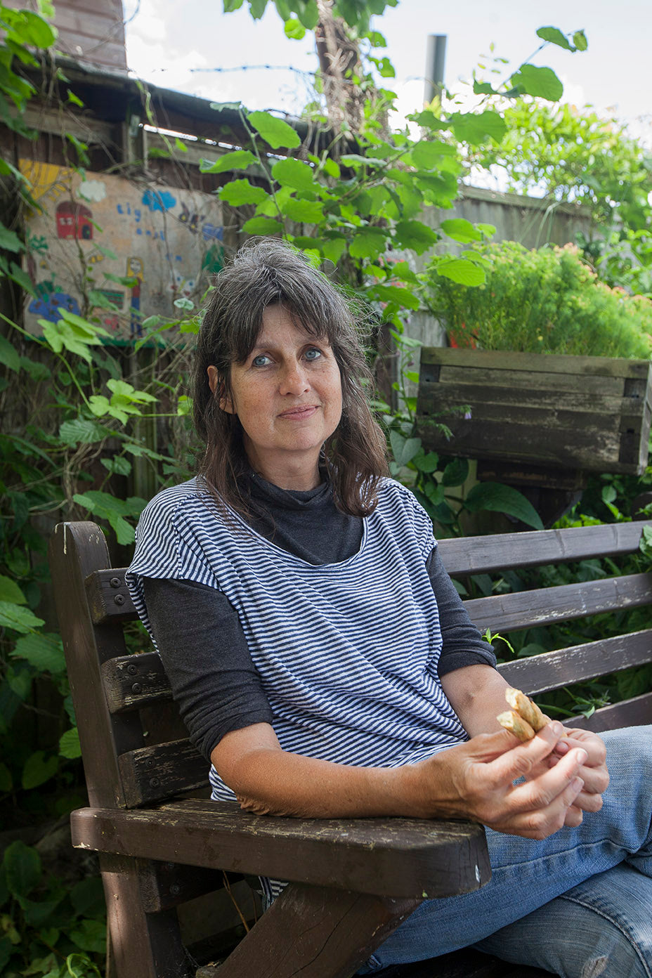 Woman sitting on a wooden bench in a garden setting