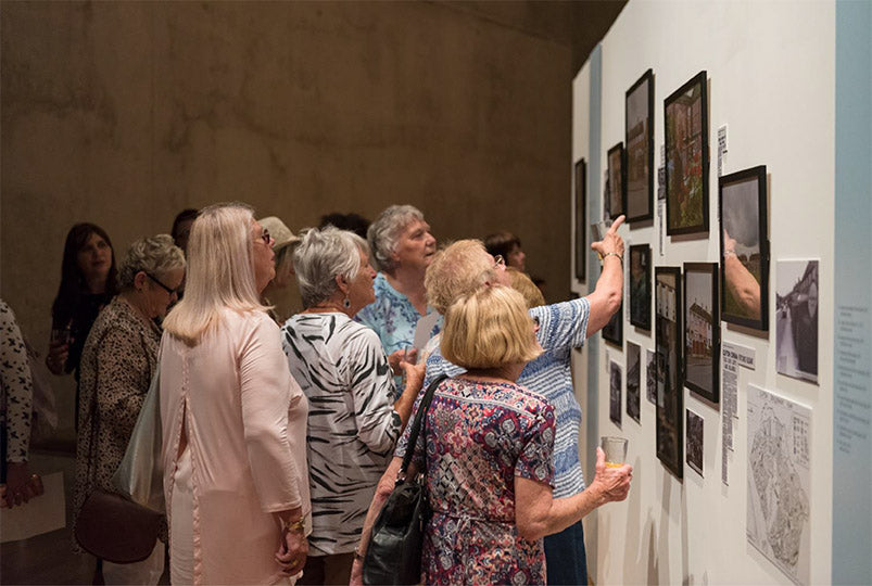 Group of people observing art exhibits in a gallery.