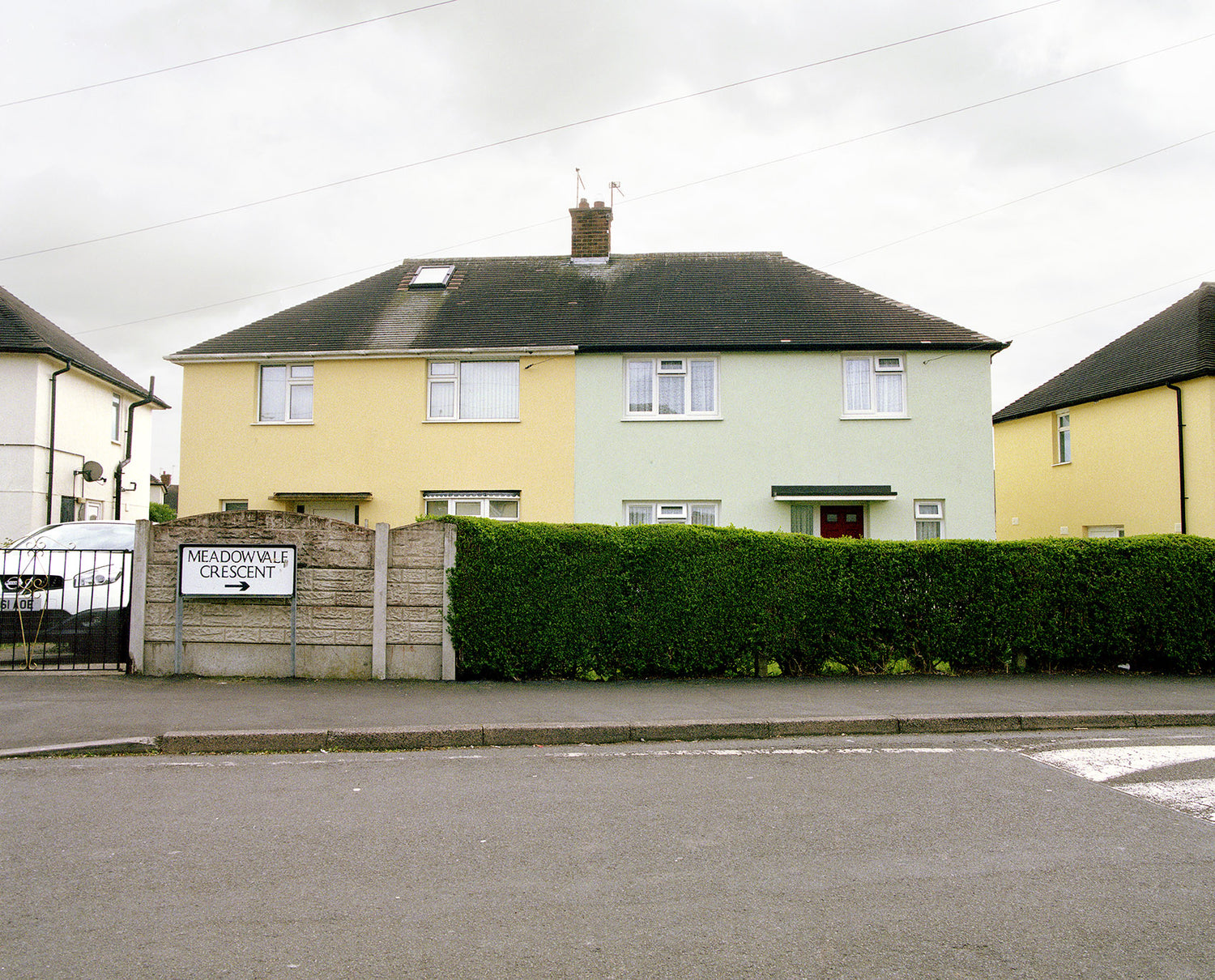 Two-story house with a sign reading 'Meadowcroft Crescent' on a cloudy day.