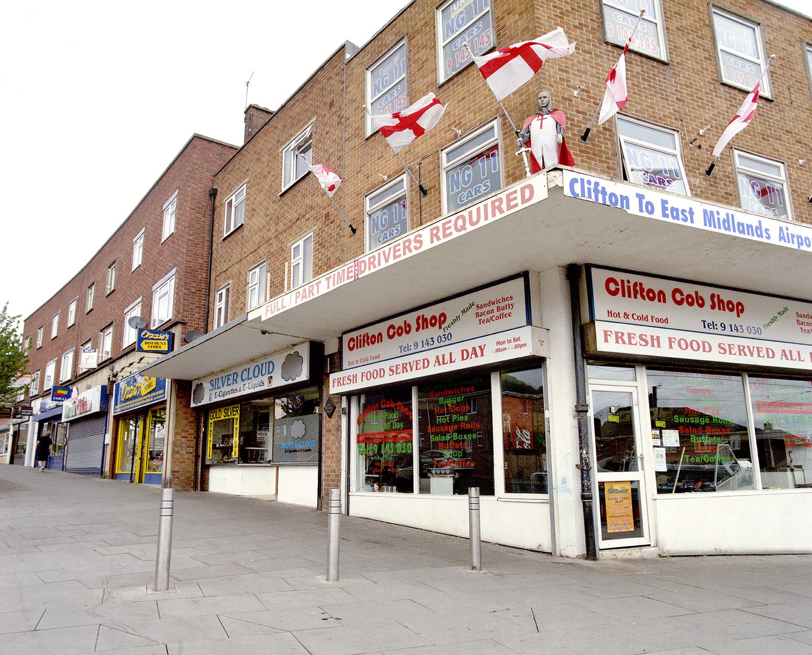 Commercial building with various shops and signs on a street corner.